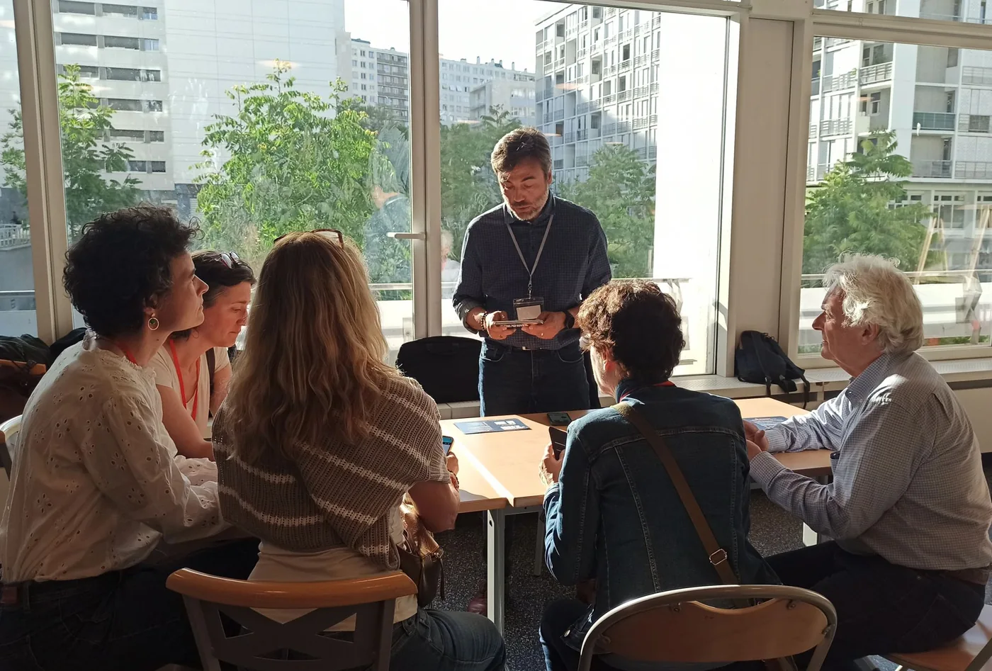 Séance de travail d'un groupe de participants Eparkéô autour d'une table, près de grandes fenêtres