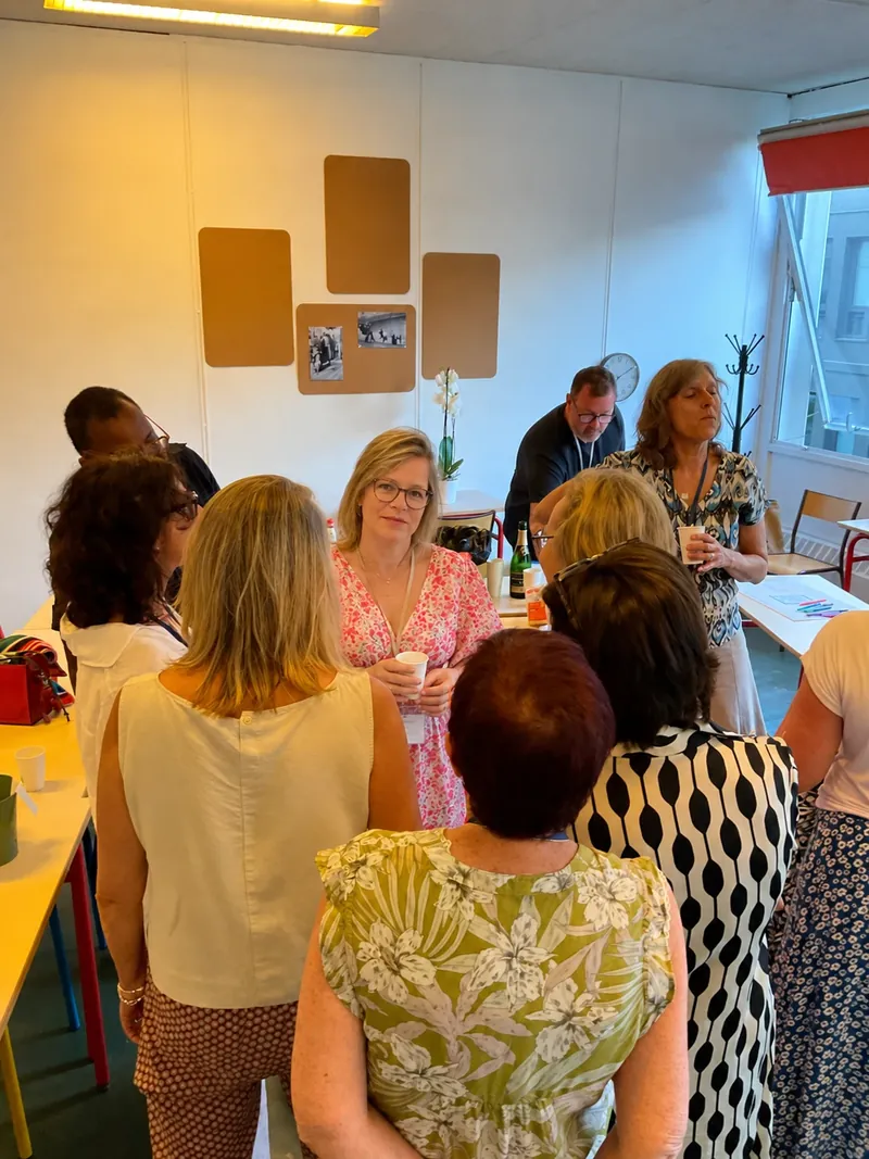 Participants échangeant en petits groupes, un verre à la main, dans une salle de rencontre